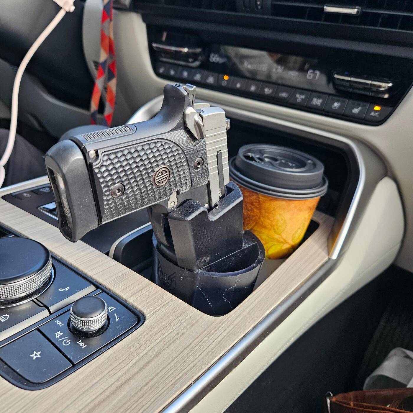 Cupolster holding a 1911 in a vehicle center console next to a coffee cup